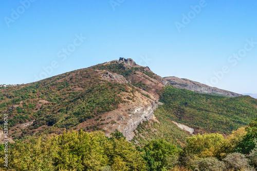 A rocky mountain ridge covered with colorful autumn trees and a clear blue sky in the background creates a stunning landscape. Kiketi, Georgia. photo