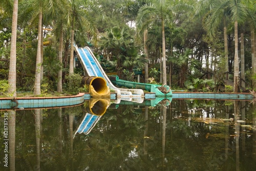 Neglected waterslide in a tropical oasis, surrounded by palm trees. Abandoned Waterpark in Hue, Vietnam.