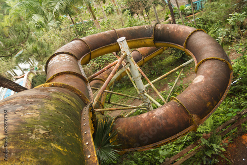 Forgotten waterslide, hidden in the depths of a lush jungle. Beauty of nature with vibrant greens and a rush of nostalgia. Abandoned Waterpark in Hue, Vietnam.