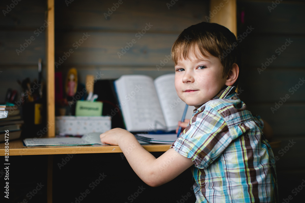 A young schoolboy does his homework, focused and diligent at his desk. A young schoolboy does his homework, focused and diligent at his desk.
