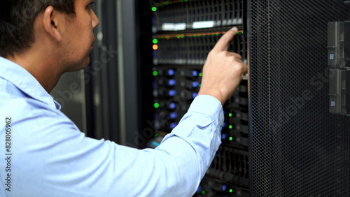 A technician in a blue shirt uses a tablet while inspecting a server rack in a modern data center, ensuring proper functionality.