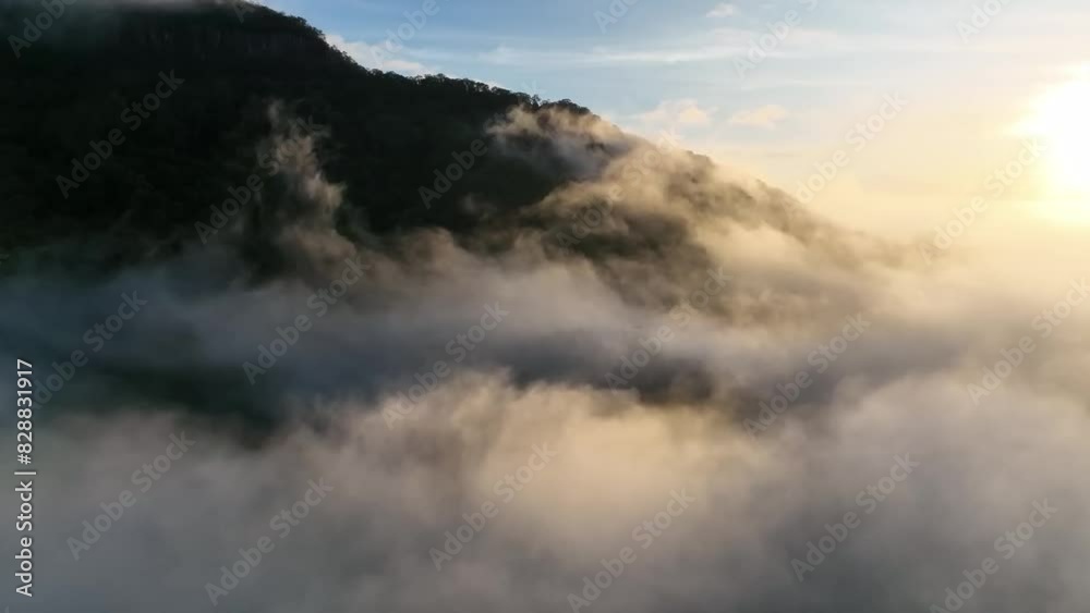 Footage capturing the sun breaking through a layer of fog over a scenic landscape, creating a beautiful and dramatic visual contrast.