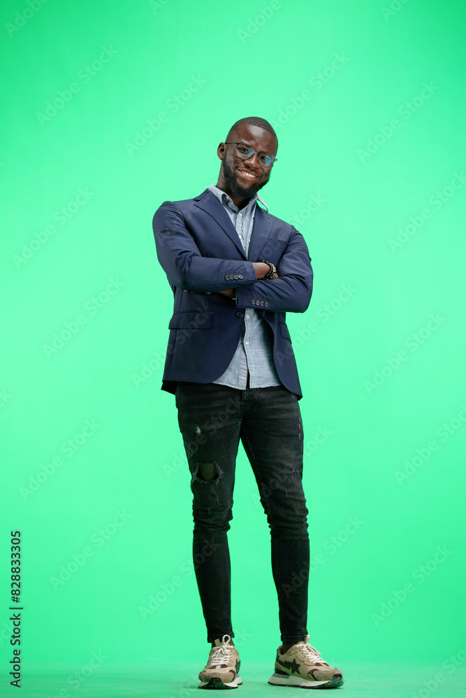A man, full-length, on a green background, crossed his arms A man, full-length, on a green background, crossed his arms