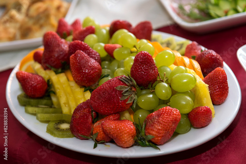 Strawberries and grapes on a plate. Assorted berries and fruits on the dining table.