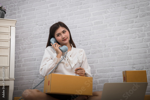 Woman receiving orders via retro telephone. Successful entrepreneur business woman with online sales and Parcel shipping in her home office.