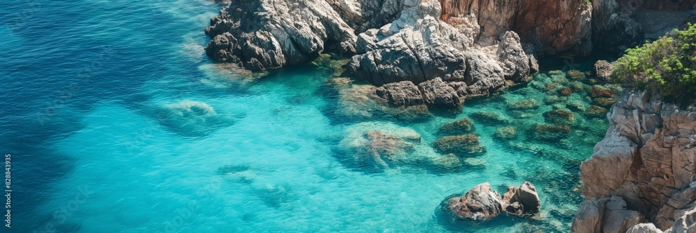 Crystal clear turquoise waters bordered by rugged cliffs, as observed from an aerial perspective above the coast