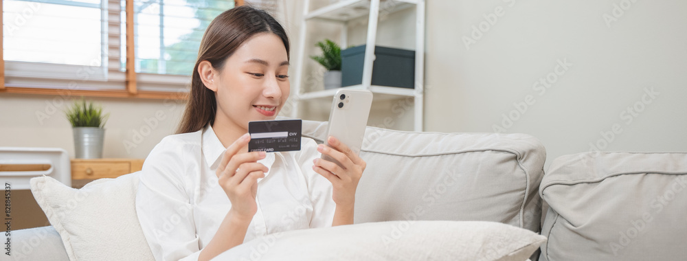 Happy Asian young woman using mobile phone shopping online and pay via credit card to get cashback bonus. Happy Asian young woman using mobile phone shopping online and pay via credit card to get cashback bonus.