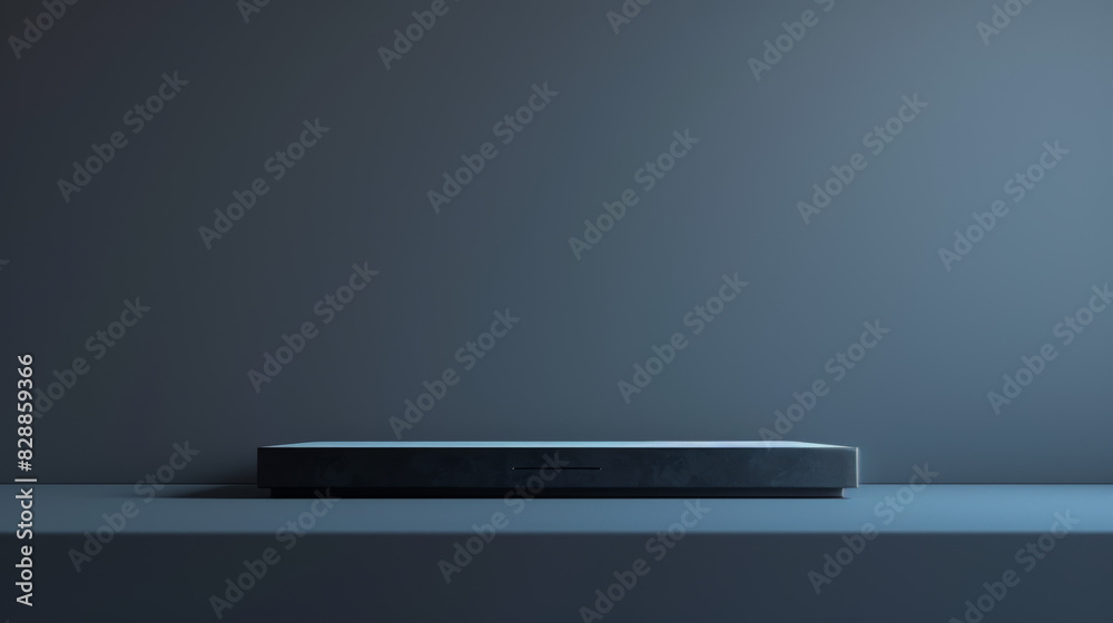 A black tablet sits on a table in front of a wall A black tablet sits on a table in front of a wall