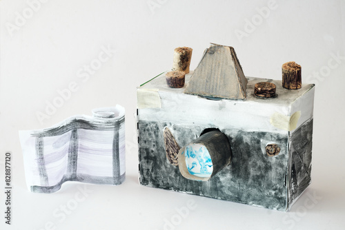 Comeback of film photography concept with grungy and funny cardboard analog camera model and film strip, free copy space