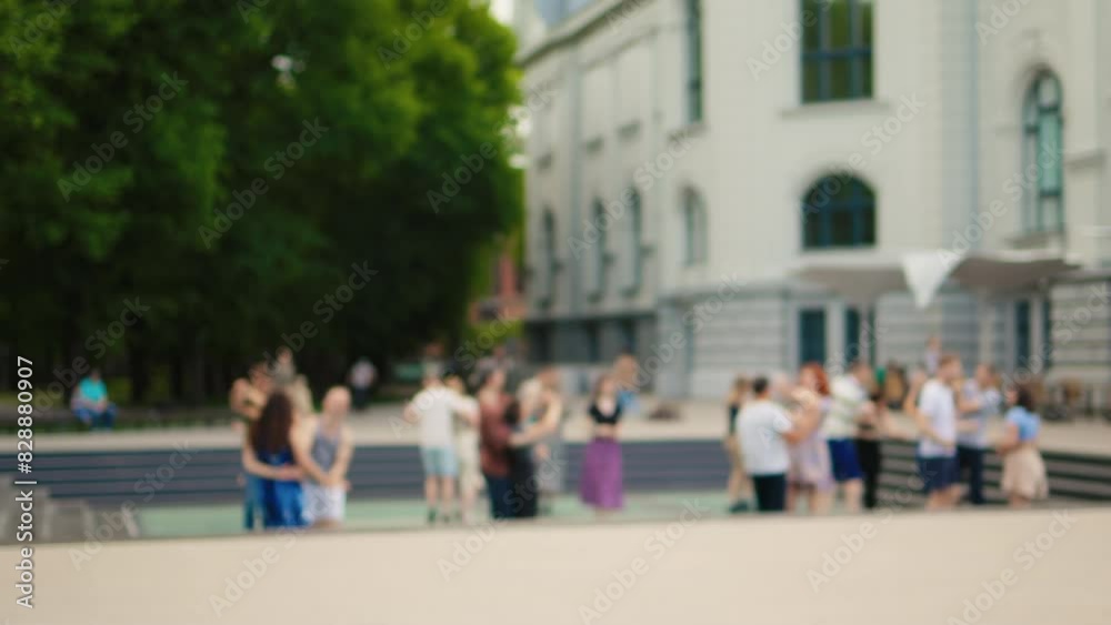People gathering outside modern building with green trees in the background on a sunny day People gathering outside modern building with green trees in the background on a sunny day