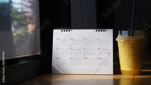 Calendar desk and iced coffee placed on business table. Desktop Calender for Planner to plan agenda, timetable, appointment, organization, management each date, month, and year on office table.