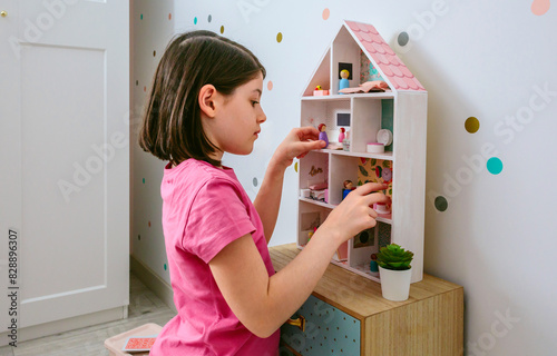 Young girl playing with dollhouse in her bedroom photo