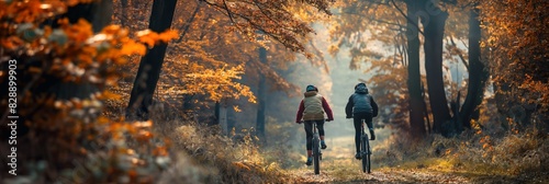 Two cyclists enjoying a leisurely ride on a forest path with autumn leaves creating a colorful atmosphere photo