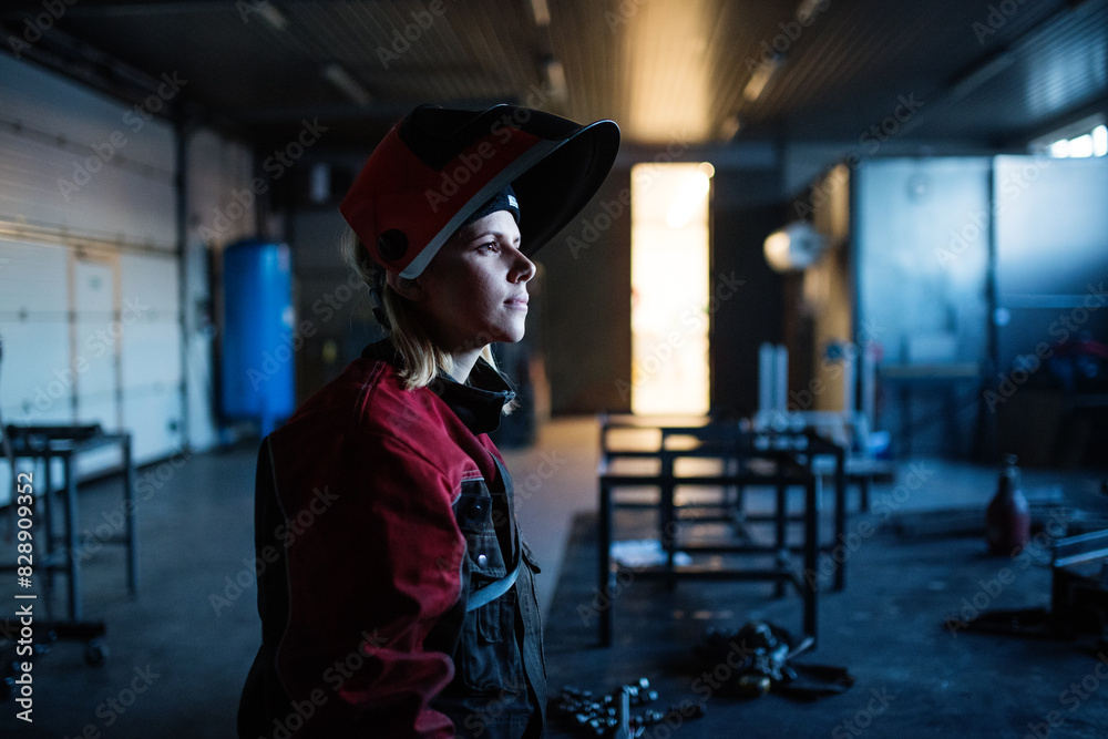 Beautiful blonde woman works as a welder in workshop, operating welding machine, wearing protective clothing and a welding mask. Beautiful blonde woman works as a welder in workshop, operating welding machine, wearing protective clothing and a welding mask.