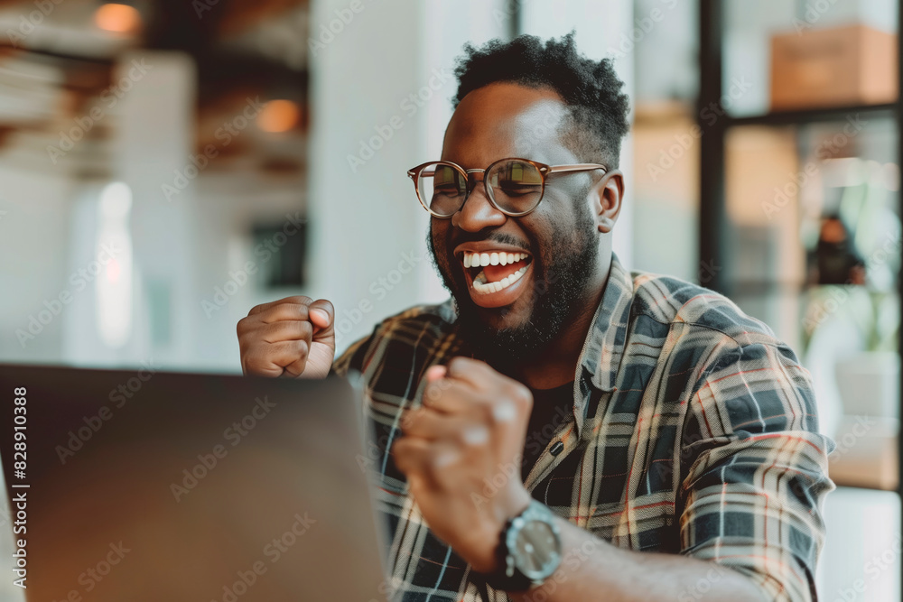 Happy man celebrating in front of a laptop in the office Happy man celebrating in front of a laptop in the office