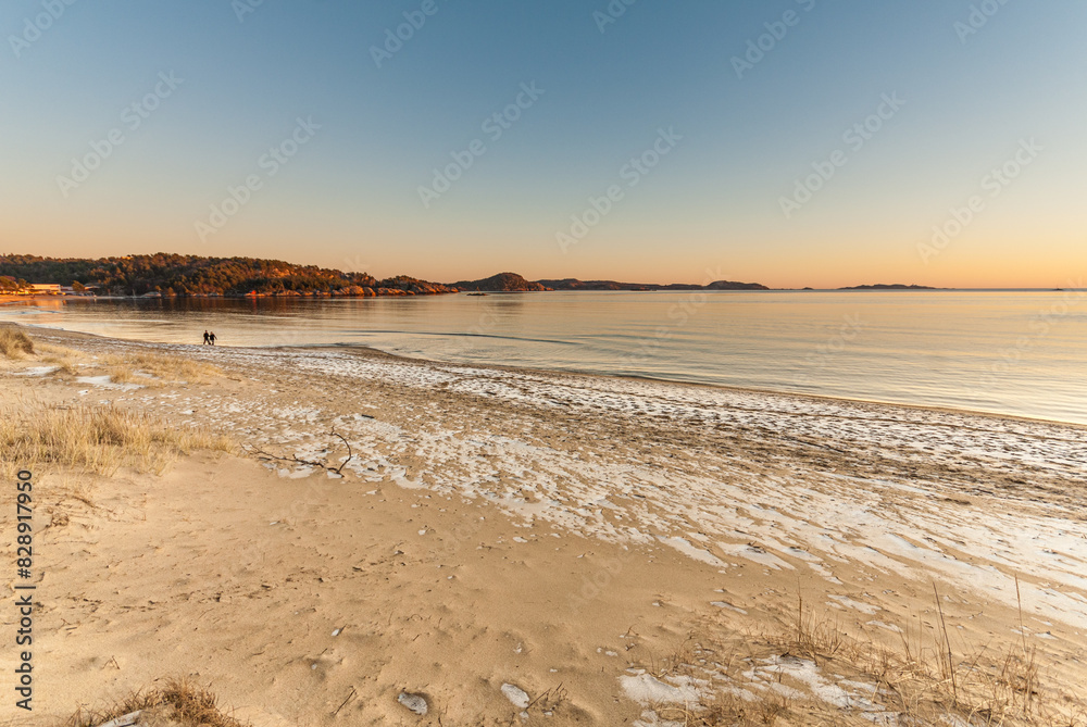 Fototapeta premium Golden glow after a sunset over an icy sand beach.