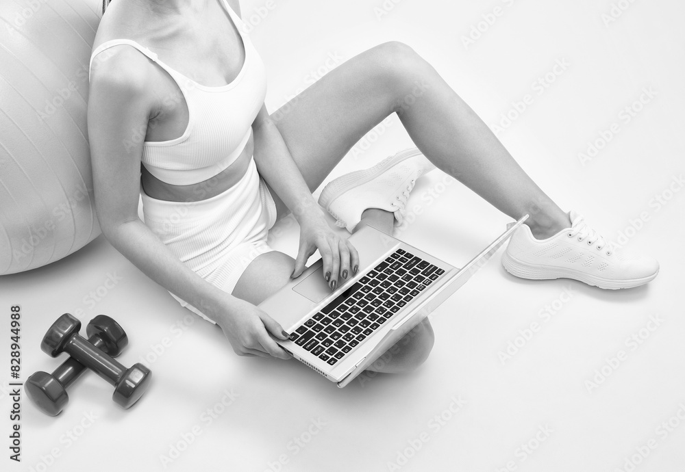 Fototapeta premium Slender dark-skinned female blogger in a white tracksuit against a white background. Healthy lifestyle, sports and diet.