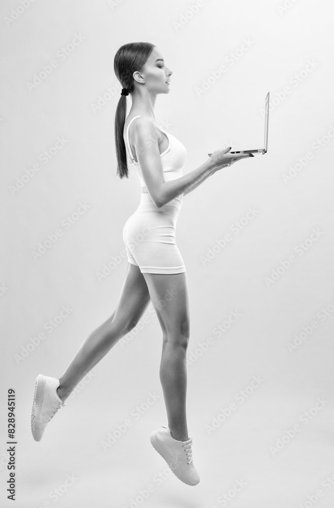 Obraz premium Slender dark-skinned female blogger in a white tracksuit against a white background. Healthy lifestyle, sports and diet.