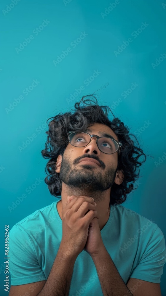 Indian man with curly hair and glasses gazing upward Indian man with curly hair and glasses gazing upward