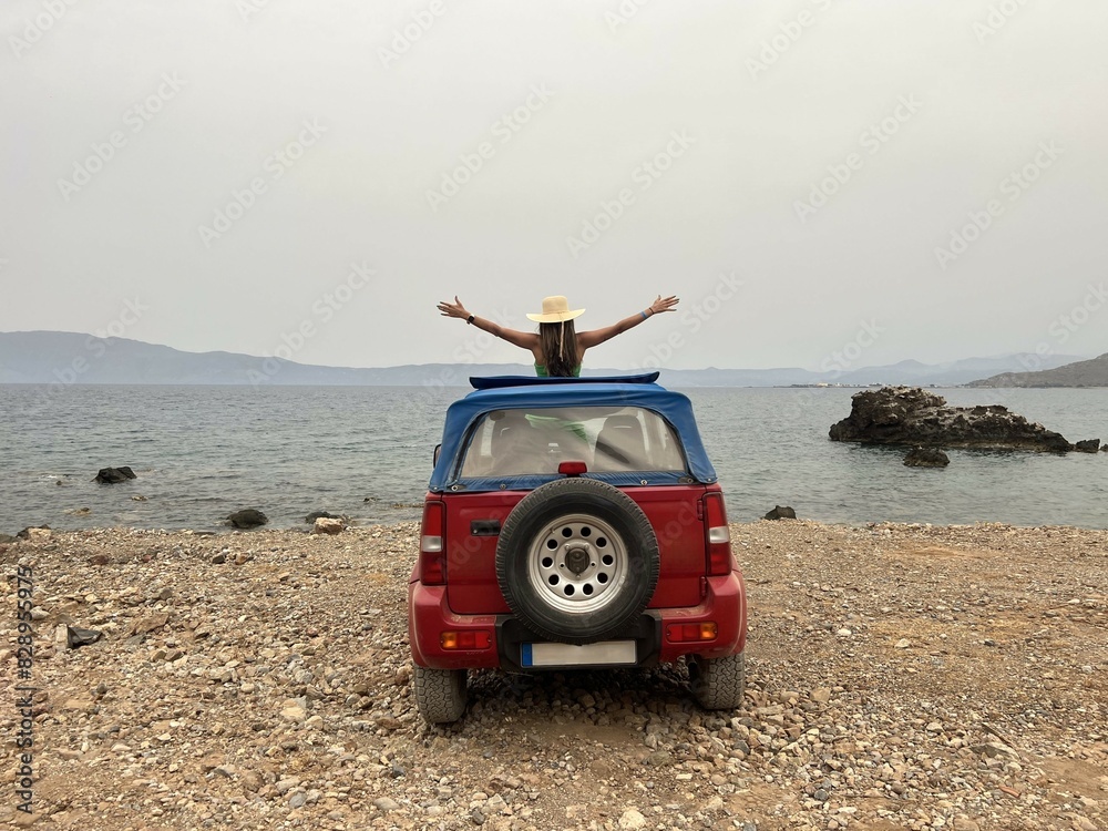 Woman standing in a convertible 4x4 with her arms raised enjoying the view. Freedom. Relax. Enjoyment. Summer Woman standing in a convertible 4x4 with her arms raised enjoying the view. Freedom. Relax. Enjoyment. Summer