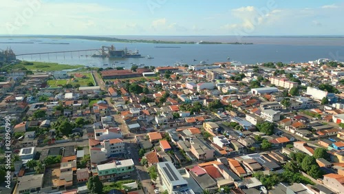 Aerial drone footage over the urban area of Santarem city in Brazil, with the city's streets and buildings and the port along the Tapajos river in the background photo