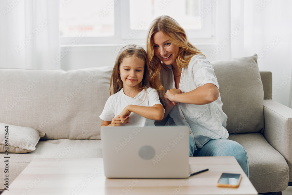 Mother and daughter bonding on the couch while exploring educational content on a laptop together Mother and daughter bonding on the couch while exploring educational content on a laptop together