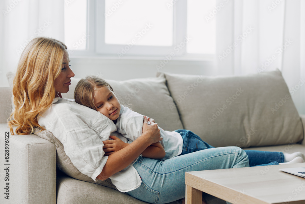 Mother and daughter bonding time, watching educational videos on a laptop while sitting on a cozy living room couch