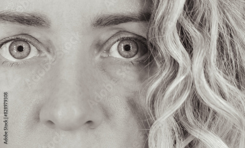 Blonde woman portrait, monochrome. Girl portrait with curly hair, closeup. Natural face with wrinlkes. Gazing woman. Skin care concept. Woman face without makeup. Human emotions. Woman in stress.  photo