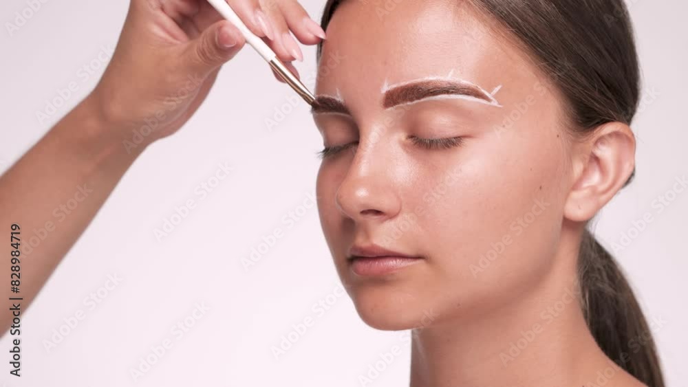 Make-up artist makes markings with white pencil for eyebrow and dyes eyebrows. Professional makeup and facial care. Make-up artist makes markings with white pencil for eyebrow and dyes eyebrows. Professional makeup and facial care.