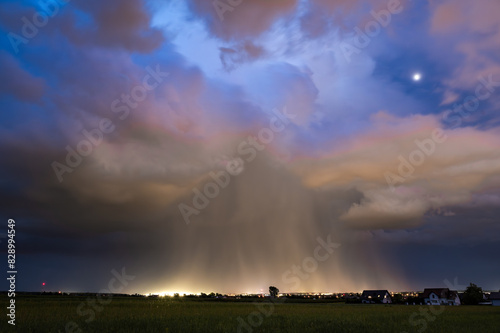 A huge storm cloud with a wall of rain in the countryside.	
