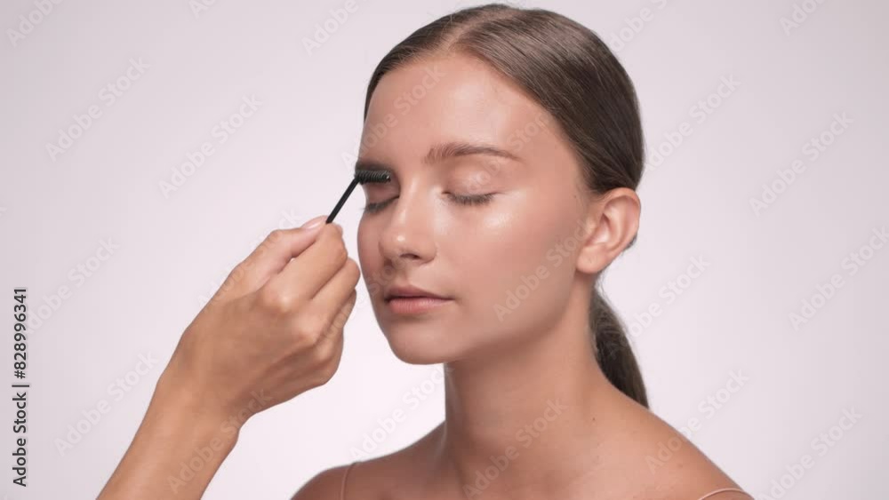 The make-up artist combs the eyebrows and makes the styling of the eyebrows with a gel. The make-up artist combs the eyebrows and makes the styling of the eyebrows with a gel.