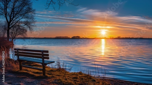 A picturesque sunset at a northern European lake, with a lone bench on the shore offering a perfect view of the suna??s reflection in the calm blue waters, surrounded by the tranquil sounds of nature.