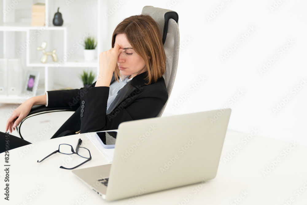 Tired frustrated and overworked business woman sitting in the office and thinking about problems in business Tired frustrated and overworked business woman sitting in the office and thinking about problems in business