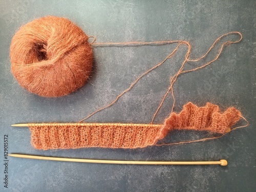 The process of knitting a jumper or sweater made of pink mohair yarn with wooden knitting needles