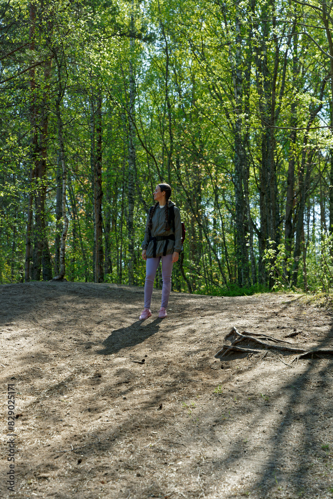 Woman hiker going down to hill and looking aside on green forest Woman hiker going down to hill and looking aside on green forest