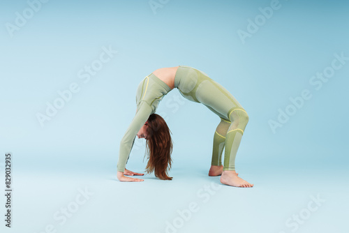 Wallpaper Mural Flexible woman wearing stylish sports uniform doing bridge, training isolated on blue background Torontodigital.ca