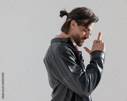 sexy unshaved man in black leather jacket making a vulgar gesture photo