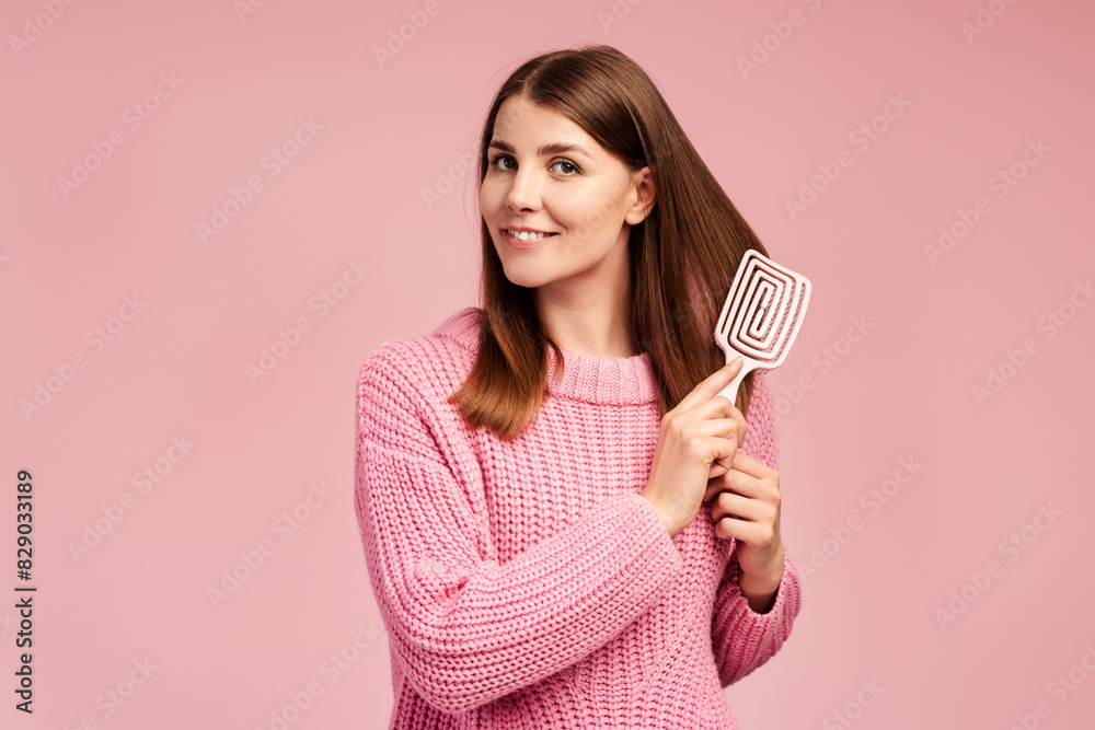 Attractive, beautiful woman in warm knitted sweater brushing her beautiful shiny hair with hairbrush Attractive, beautiful woman in warm knitted sweater brushing her beautiful shiny hair with hairbrush