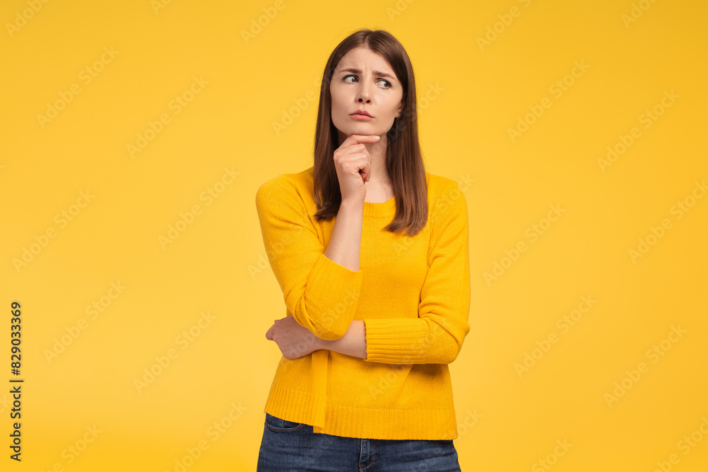 Serious middle aged woman looking away, choosing something, standing isolated on yellow background Serious middle aged woman looking away, choosing something, standing isolated on yellow background