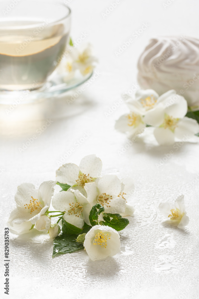 Fragrant jasmine tea in a glass cup with marshmallows on a white wooden table. Fragrant jasmine tea in a glass cup with marshmallows on a white wooden table.