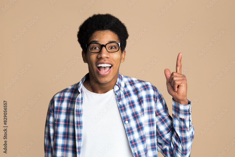 Guy having idea, pointing finger up and looking at camera over light background Guy having idea, pointing finger up and looking at camera over light background