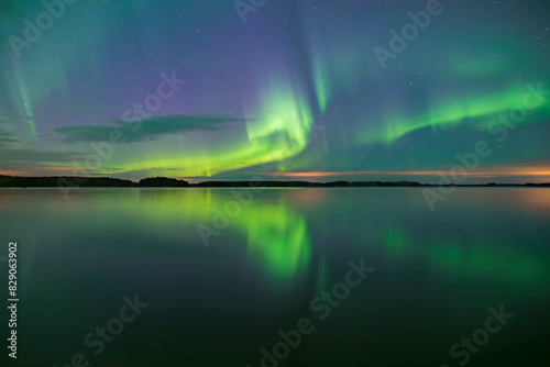 Northern lights dancing over calm lake in Farnebofjarden national park in north of Sweden. photo
