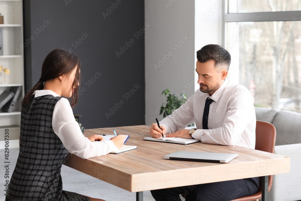 Human resources manager interviewing applicant at table in office Human resources manager interviewing applicant at table in office
