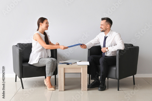 Human resources manager interviewing applicant near light wall in office