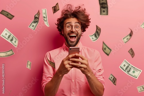 Excited man celebrating financial windfall with falling dollar bills while using smartphone