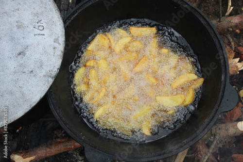 Potatoes in the process of frying. Rustic fries in a cauldron. Cooking in nature