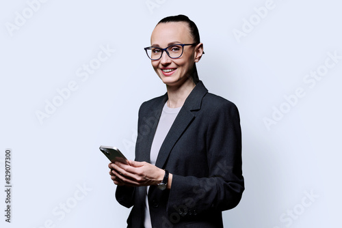 Adult smiling woman with smartphone on white studio background