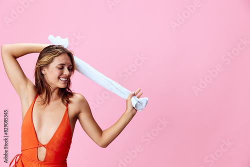 Vibrant summer vibes happy woman in bright orange swimsuit holds white towel on pink background