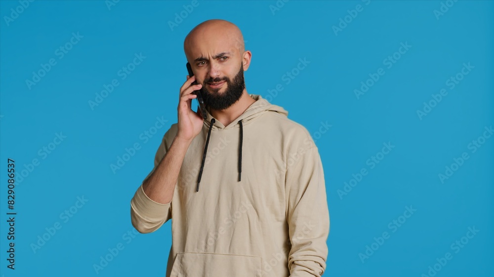 Arab person answering phone call in front of camera, talking to his friends on remote chat with smartphone. Young adult using mobile phone communication to discuss with people. Camera 1. Arab person answering phone call in front of camera, talking to his friends on remote chat with smartphone. Young adult using mobile phone communication to discuss with people. Camera 1.