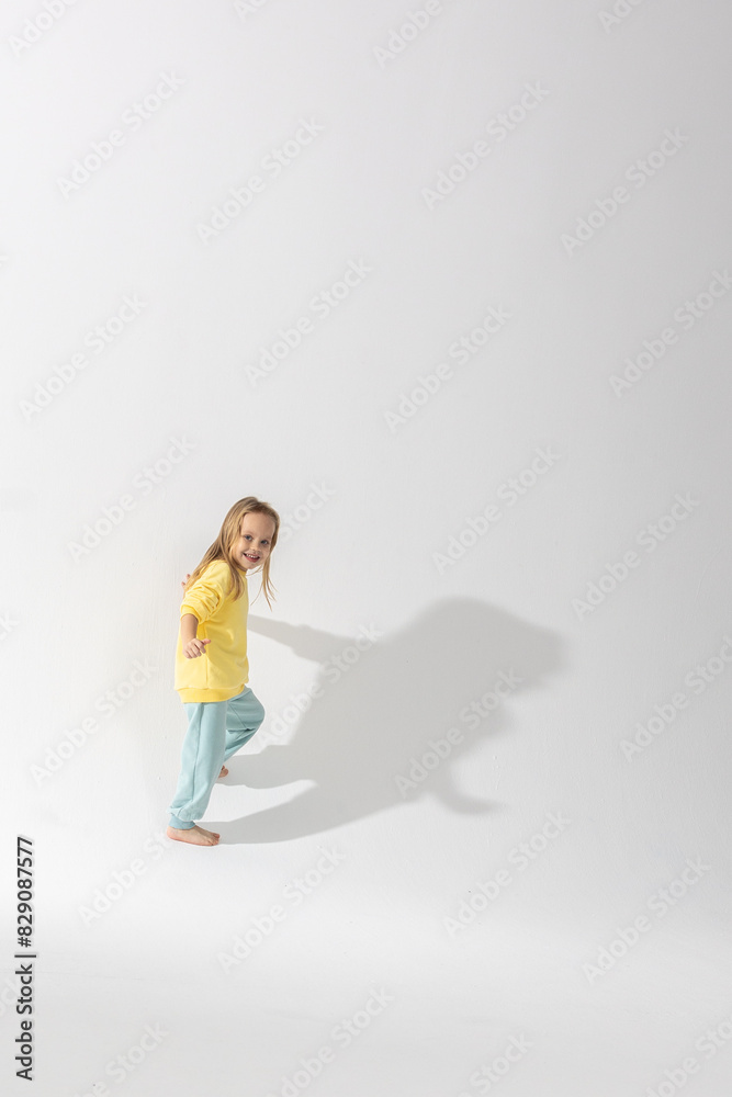 Portrait of beautiful cute little toddler girl. Child with funny face in yellow sweatshirt. Pretty smile kid in studio on white background. High quality photo Portrait of beautiful cute little toddler girl. Child with funny face in yellow sweatshirt. Pretty smile kid in studio on white background. High quality photo